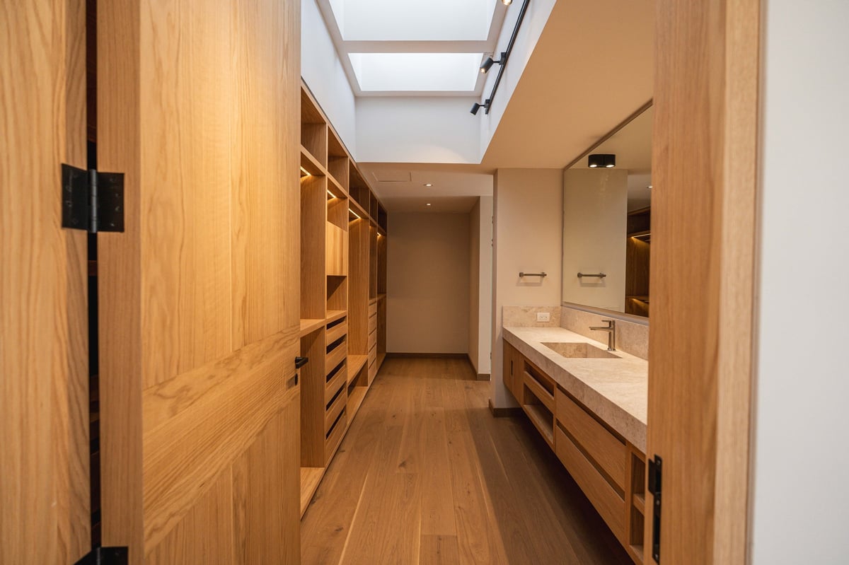 Modern luxury bathroom with wooden cabinetry, double vanity sink, and skylight in contemporary home interior